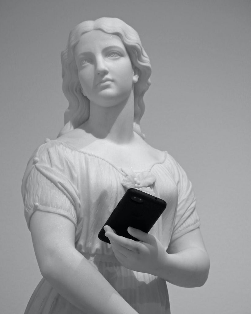 old statue of young woman with smartphone in museum