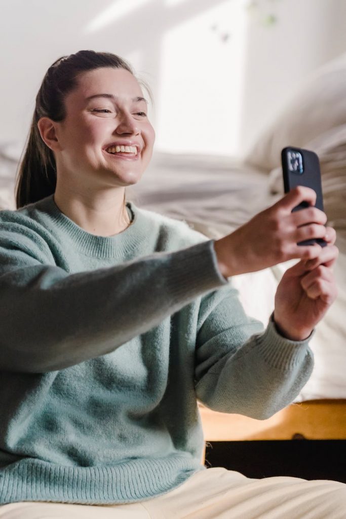smiling woman taking selfie on smartphone