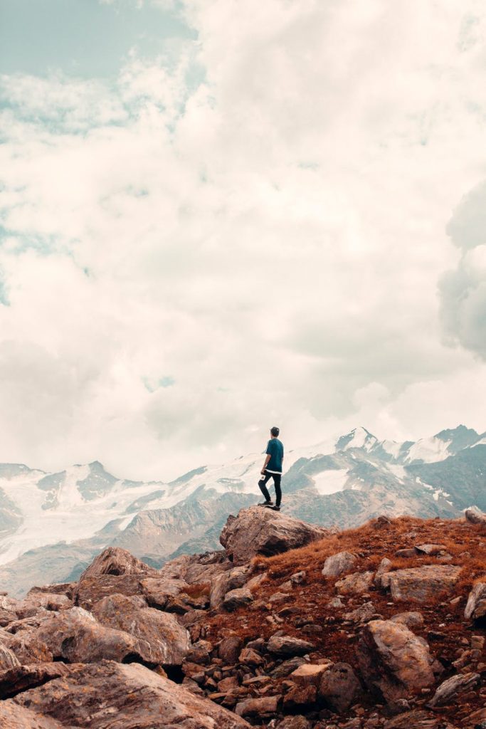 a man standing on rocky mountain under cloudy sky