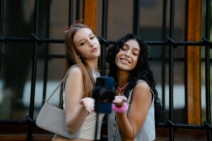 young fashionable girls taking a picture with a smartphone on a tripod